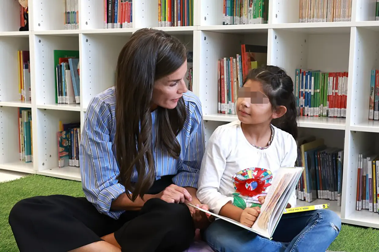 La reina Letizia mirando un libro con una niña