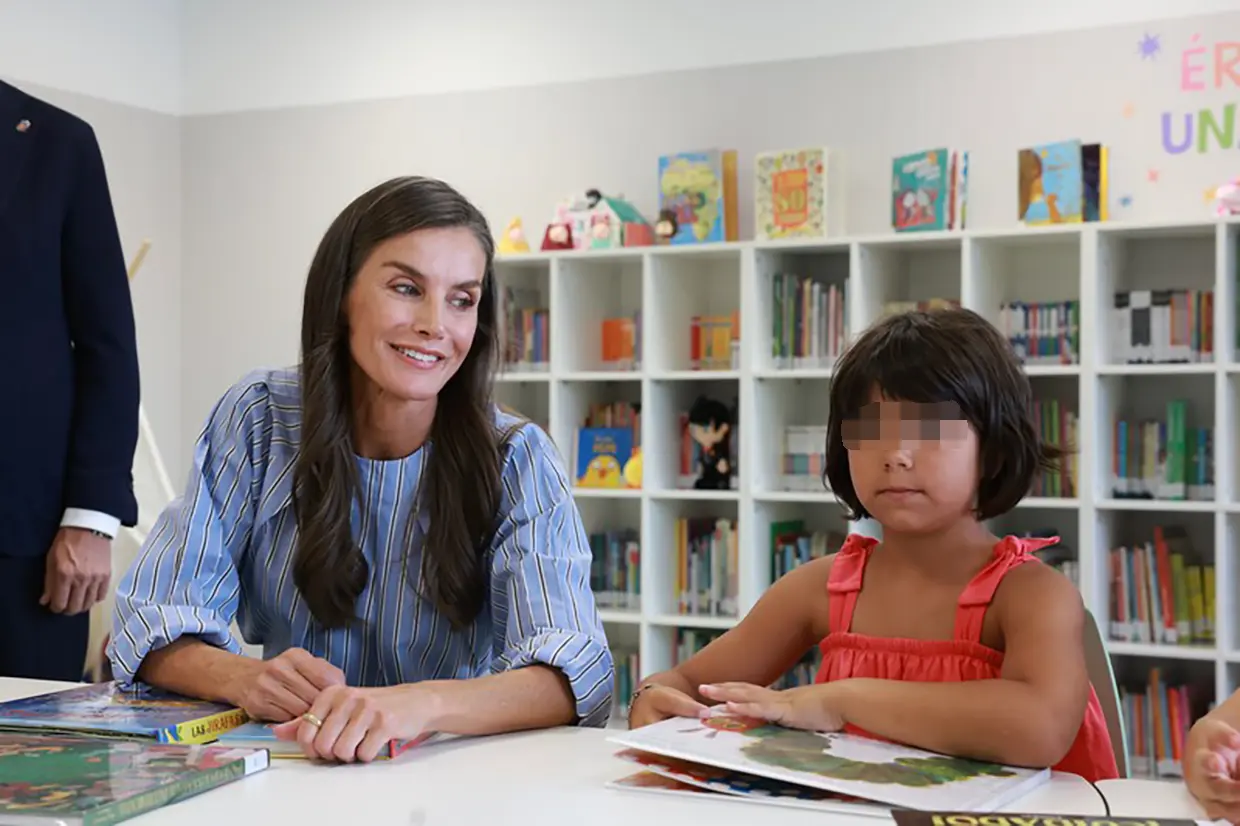 La reina Letizia mirando un libro con una niña
