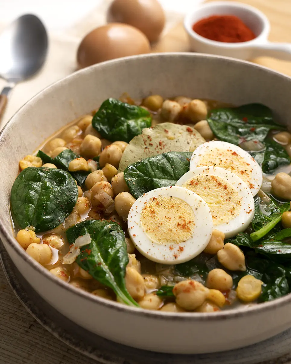 Plato servido de garbanzos con espinacas y huevo duro recién preparado