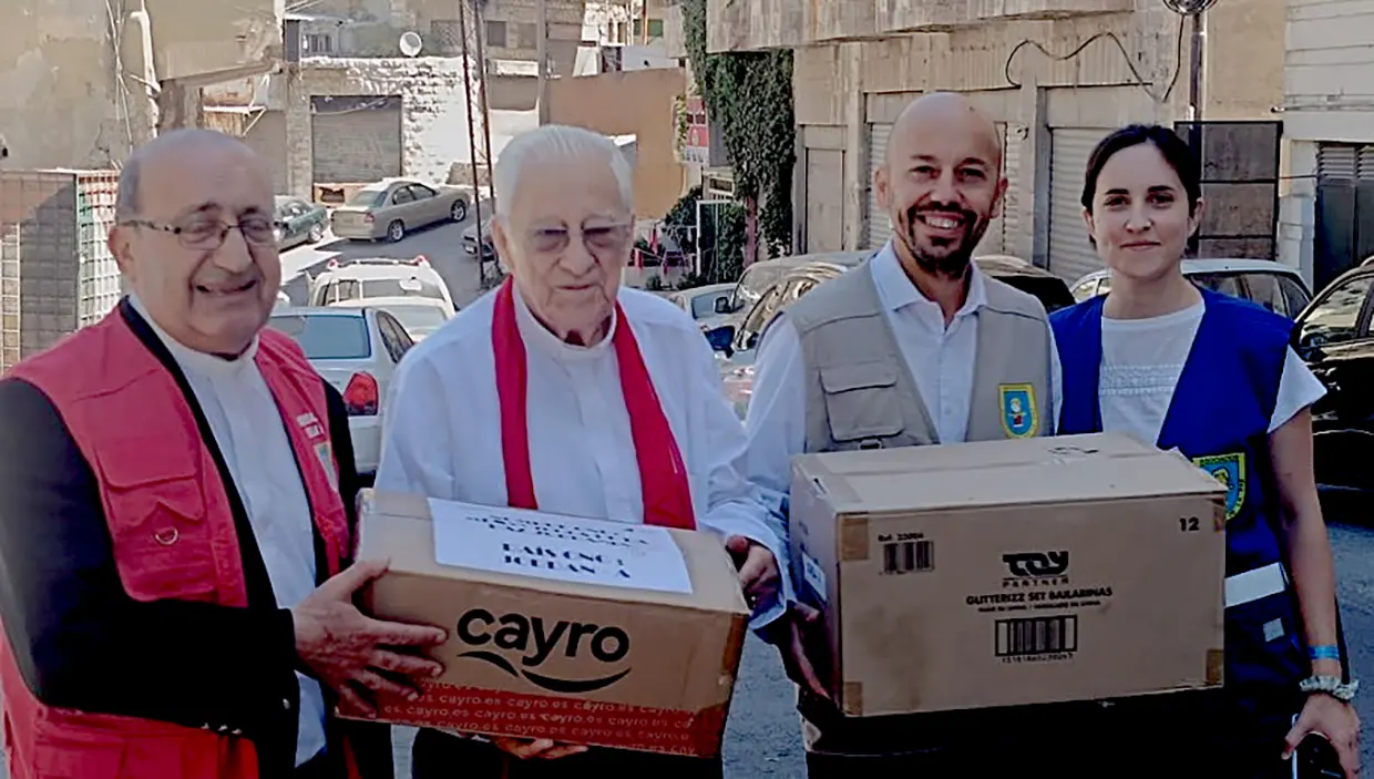 El padre Ángel cargando con cajas de ayuda humanitaria.
