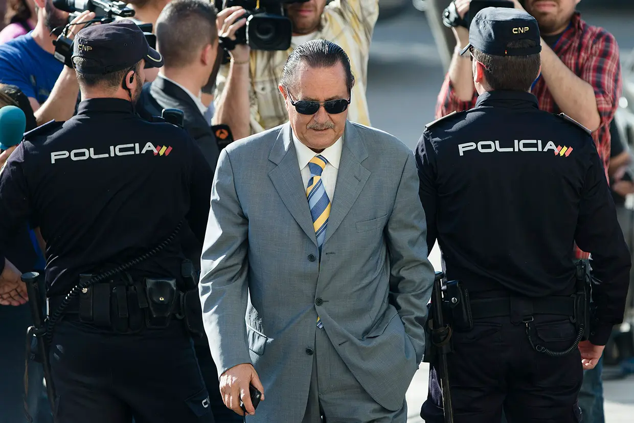 Julián Muñoz con traje entre dos policías