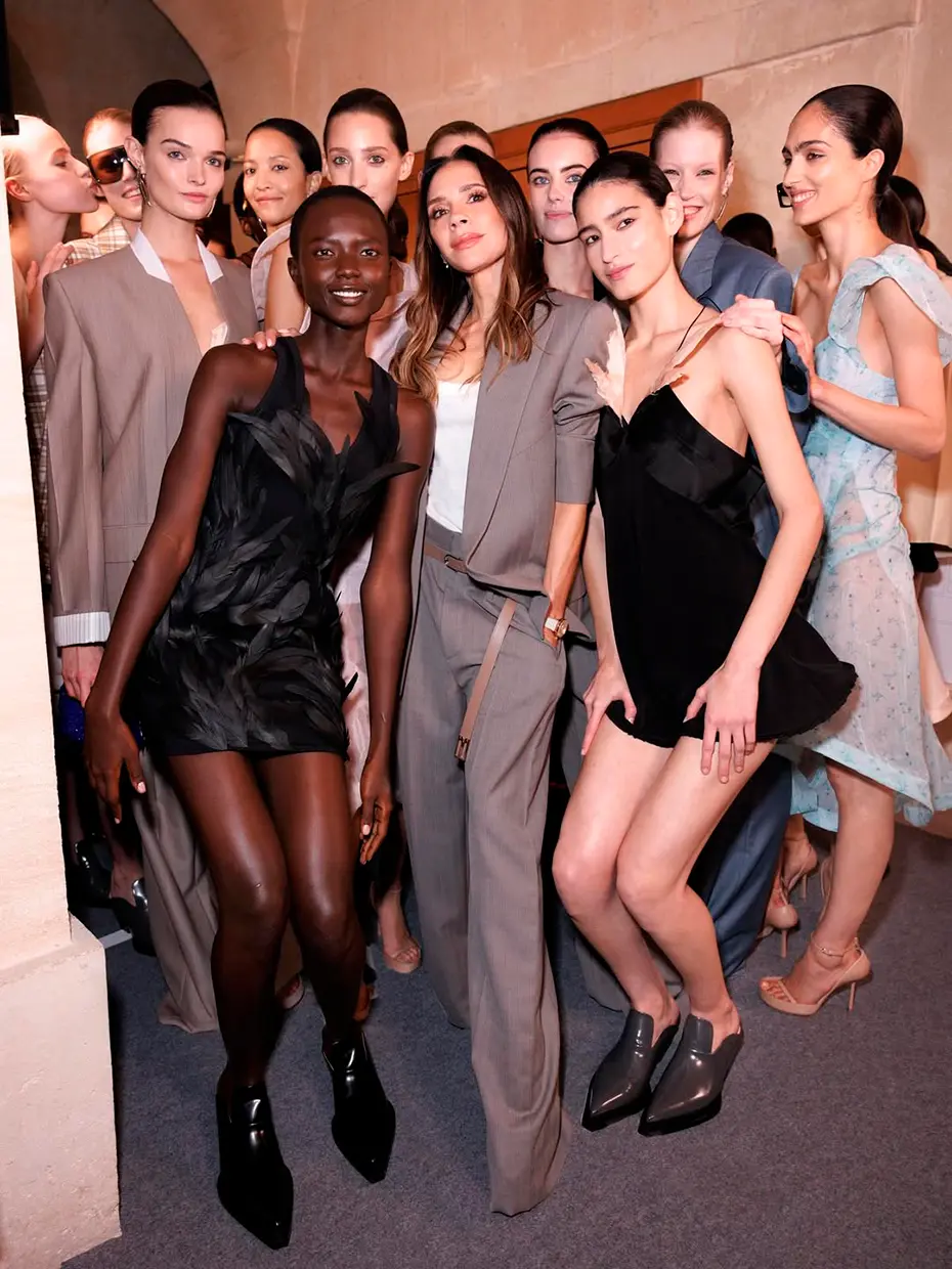 Victoria Beckham posa junto a mujeres modelos de su marca de ropa.